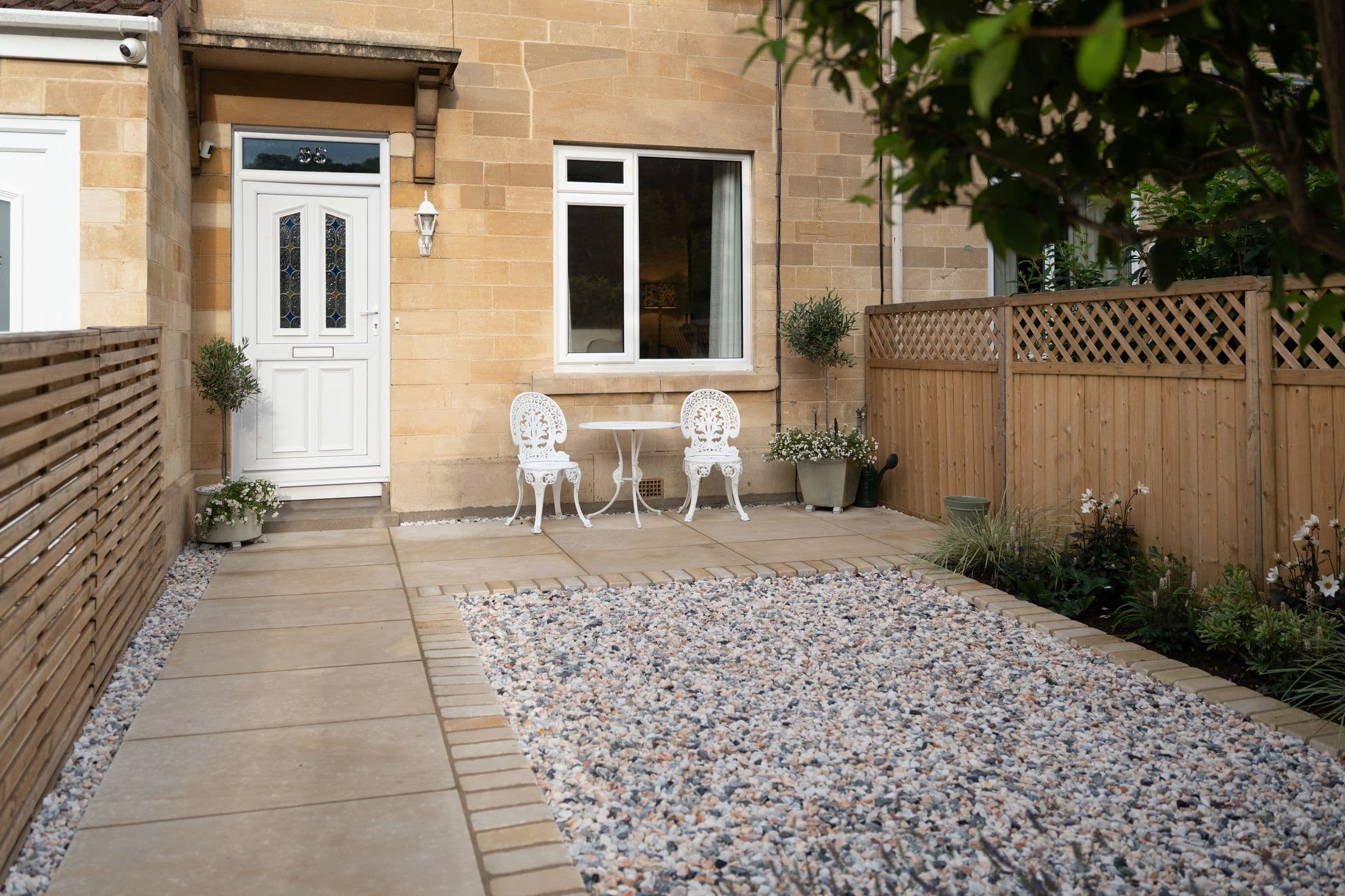 The front of the house, with the white table and chairs set by the door.