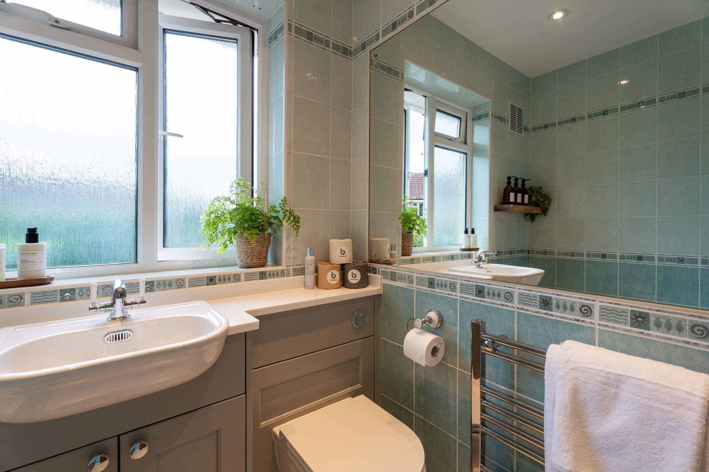 The bathroom basin below the window, with the heated towel rail alongside.