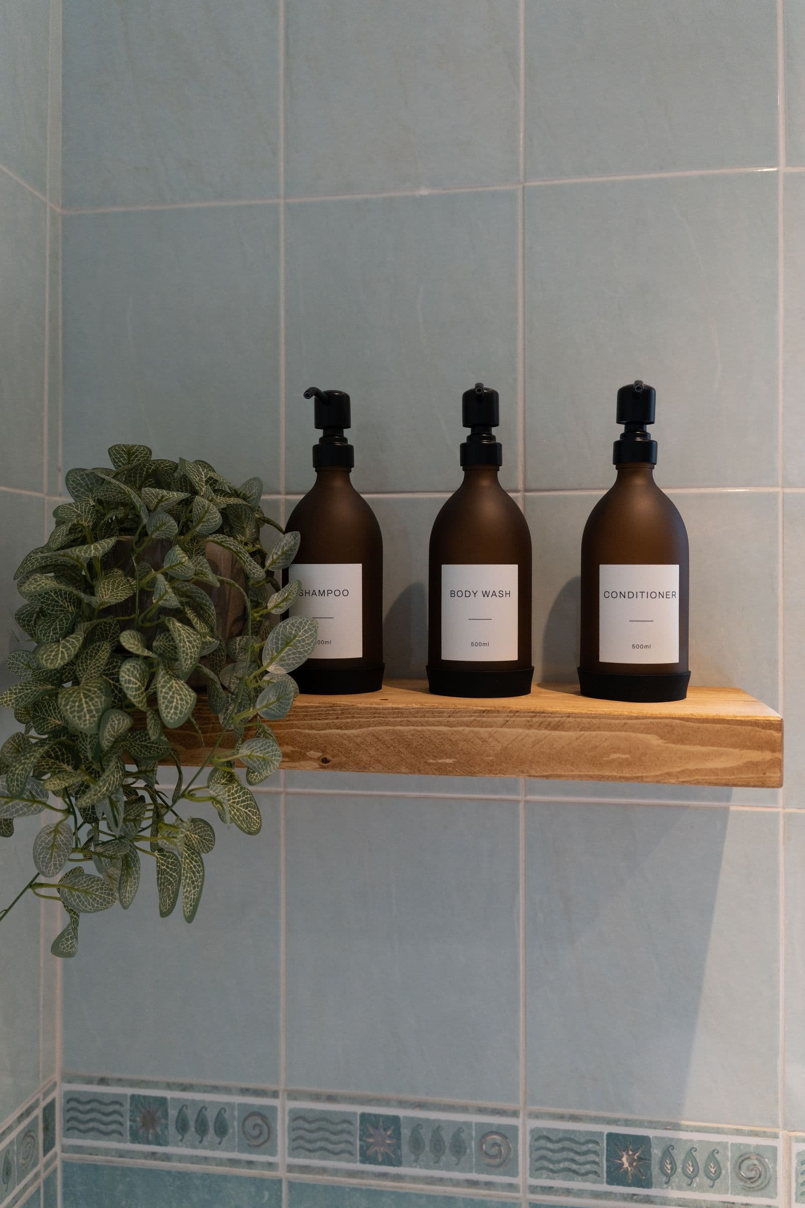 The toiletry bottles on the wooden shelf above the bath.