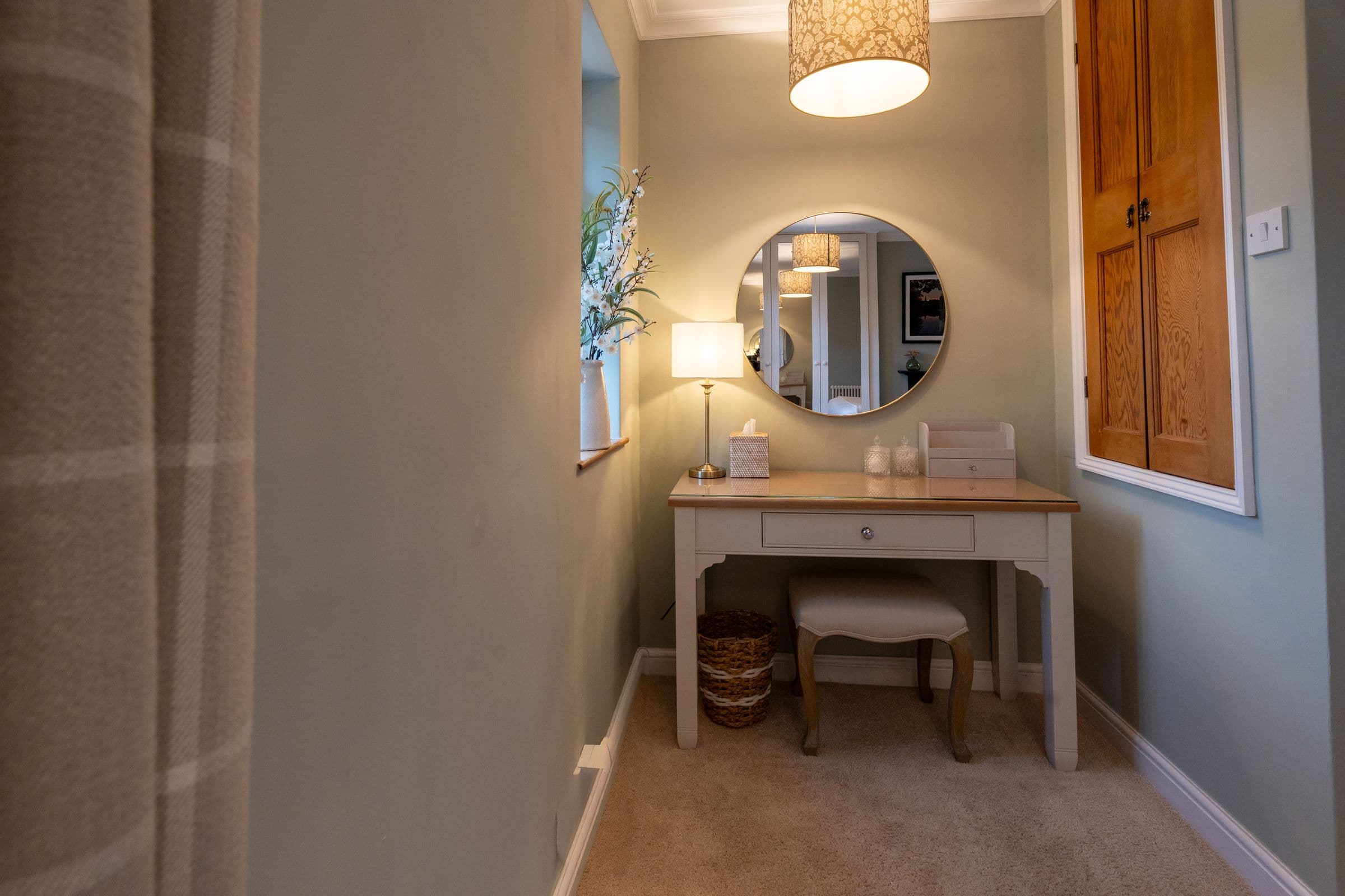 The dressing table with its round mirror and lamp, in the corner of the main bedroom.