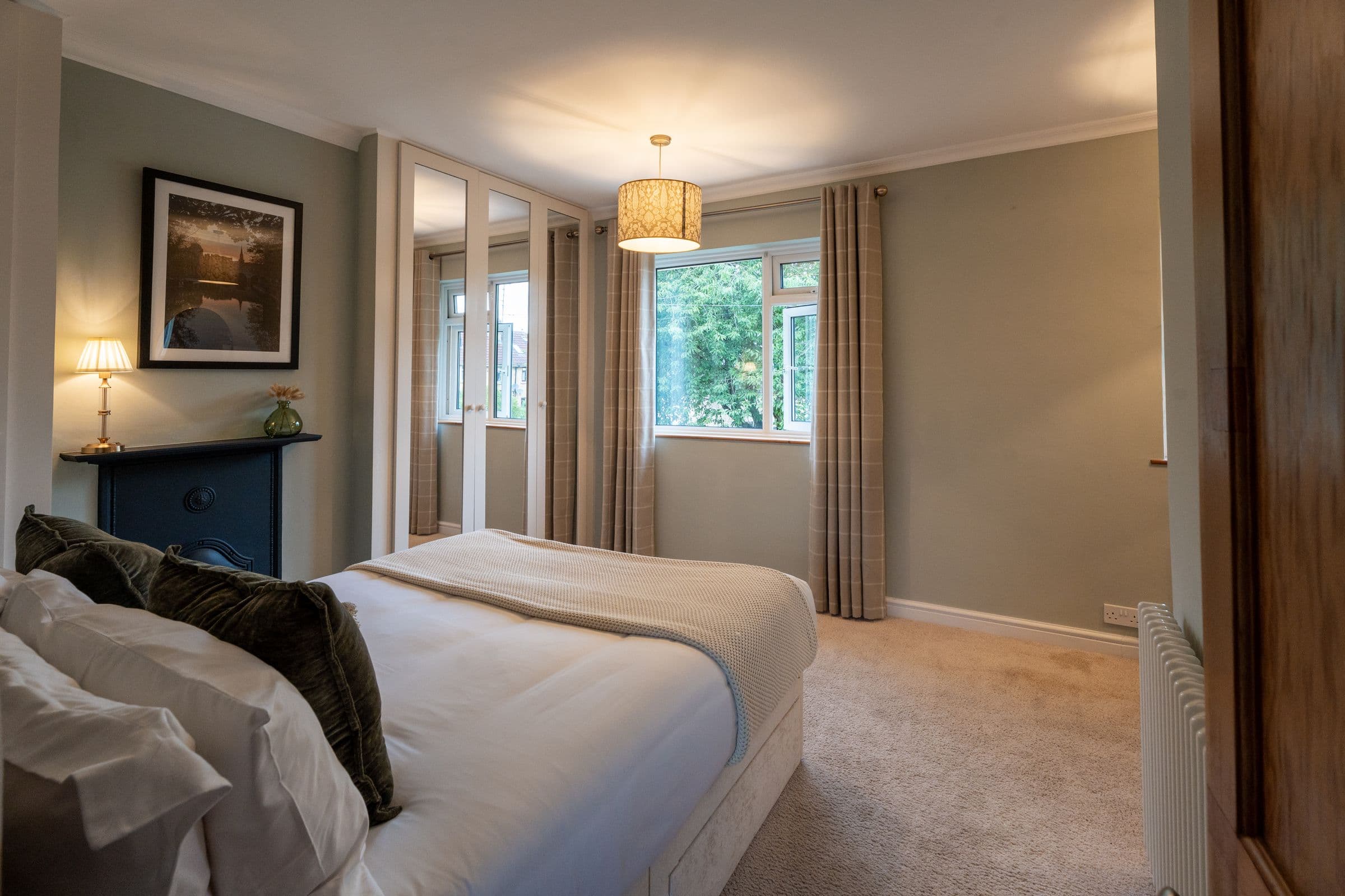 The main bedroom, with the bed, original fireplace and mirrored wardrobes.