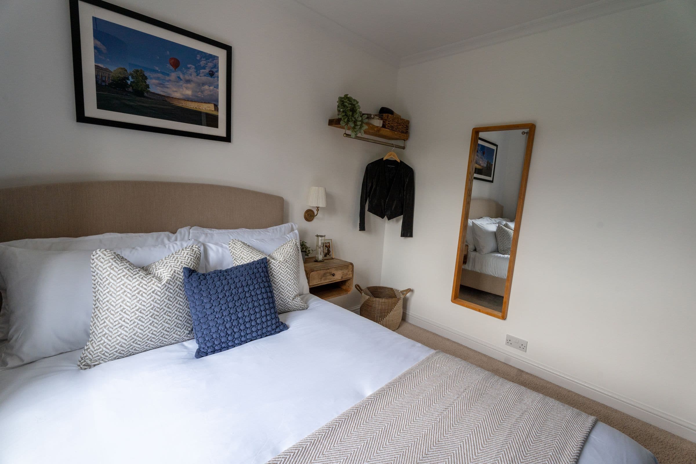 The second bedroom with the mirror and shelf styled beside the bed.