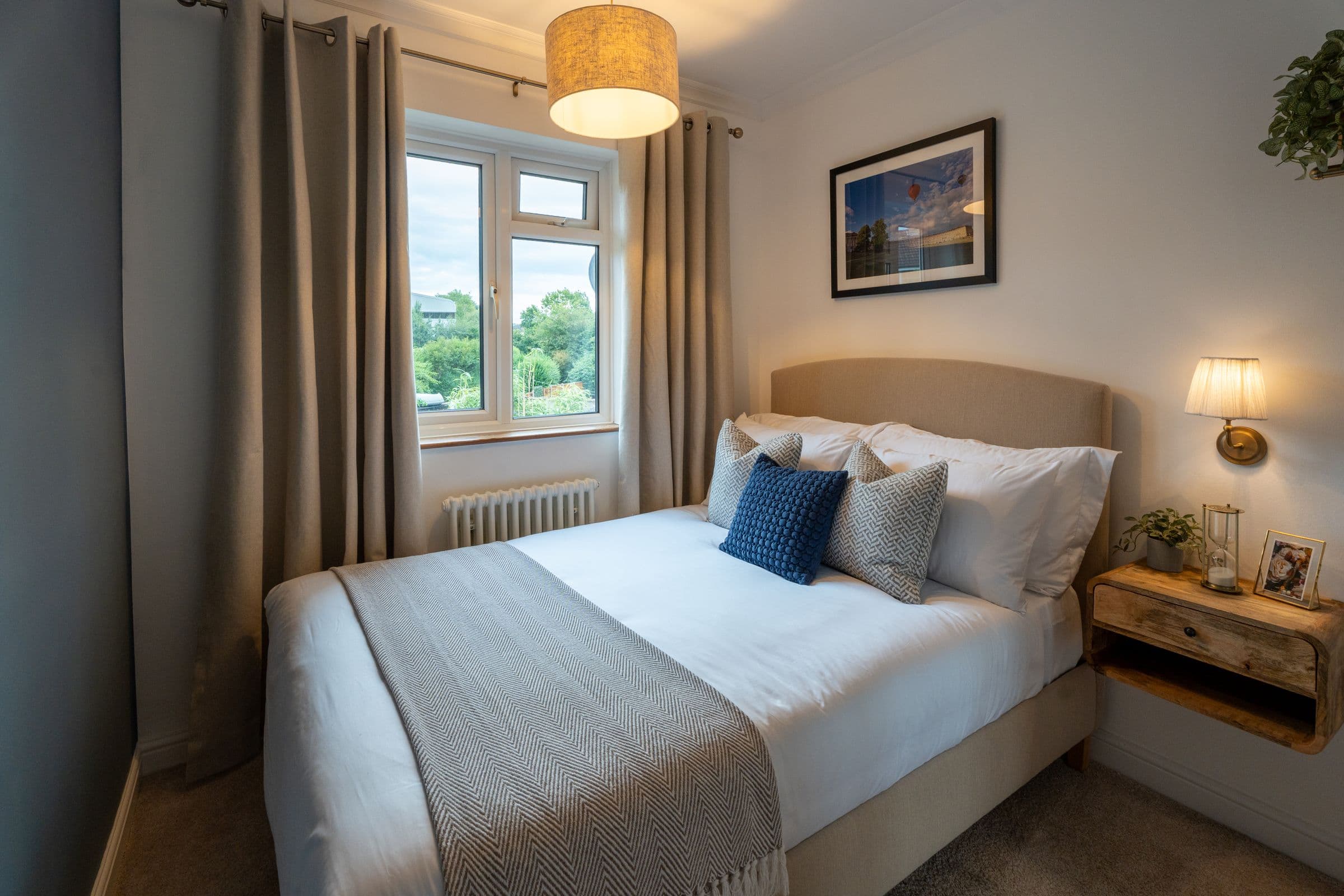 The second bedroom, with the bed made up in white and the window over the trees.