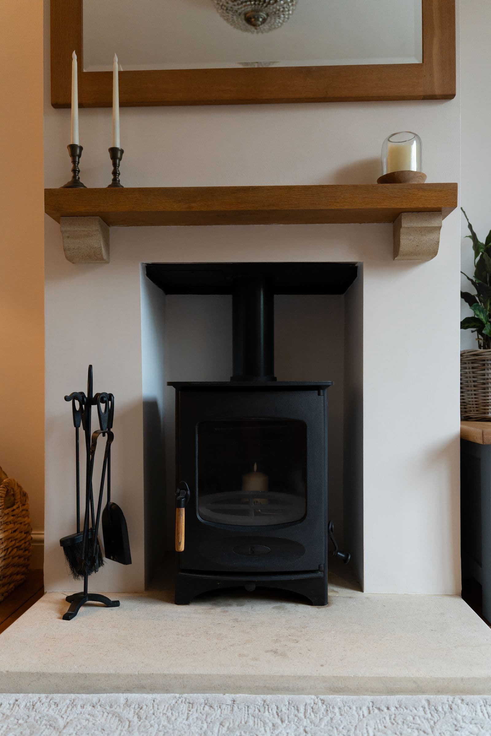 The wood burner and its tools beneath the oak mantel.