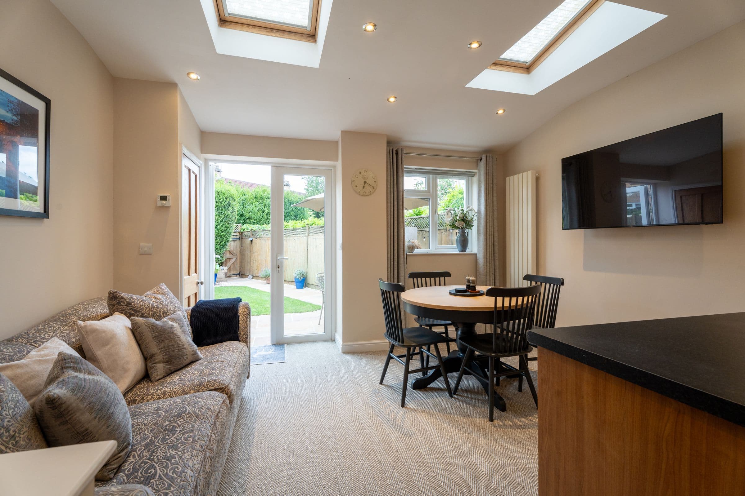 The garden room with the doors onto the garden, sofa and dining table either side.