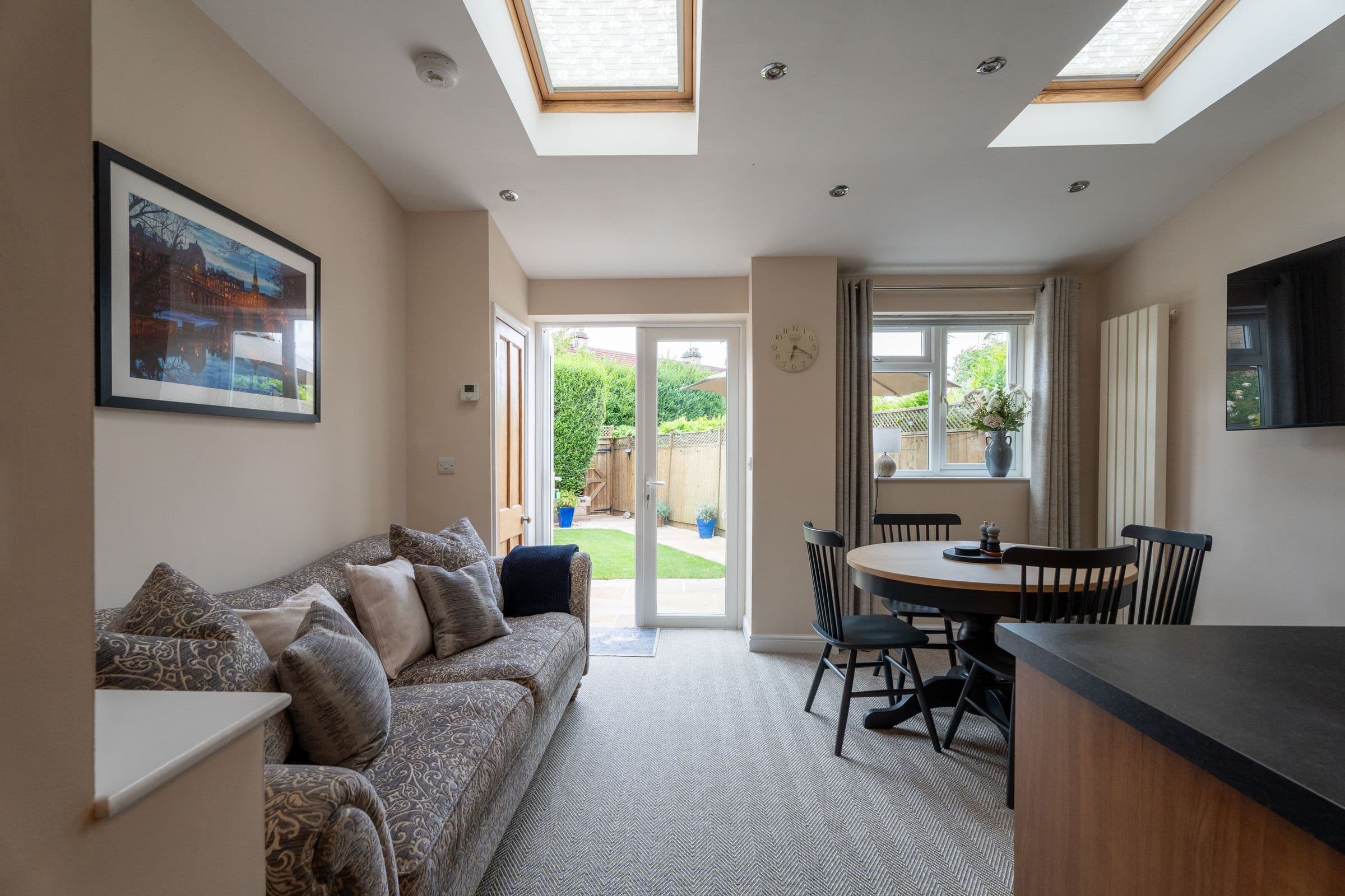 The garden room under its skylights — sofa on one side, dining table on the other, doors onto the garden.