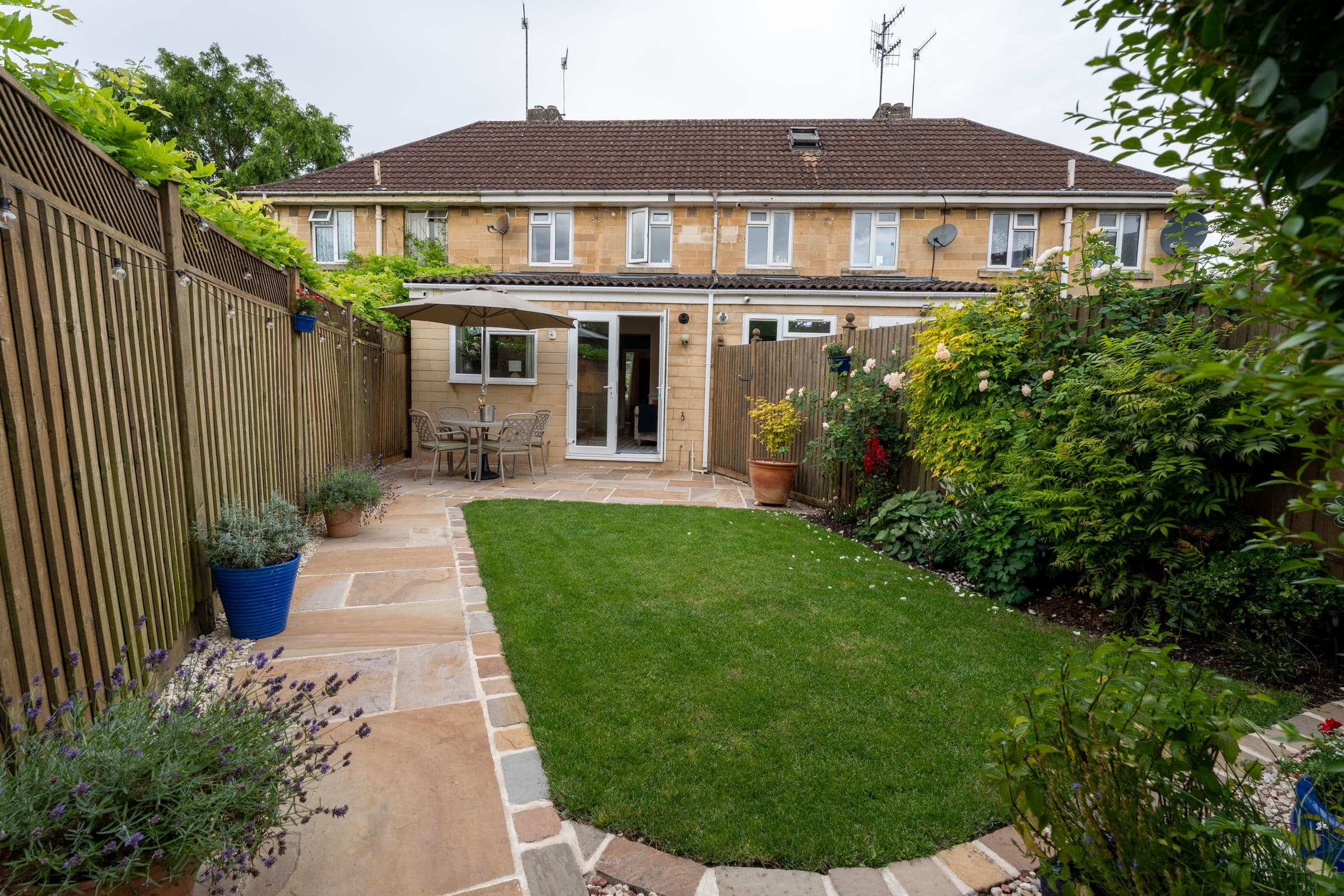 The rear of the house from the end of the garden, with the patio table by the doors.