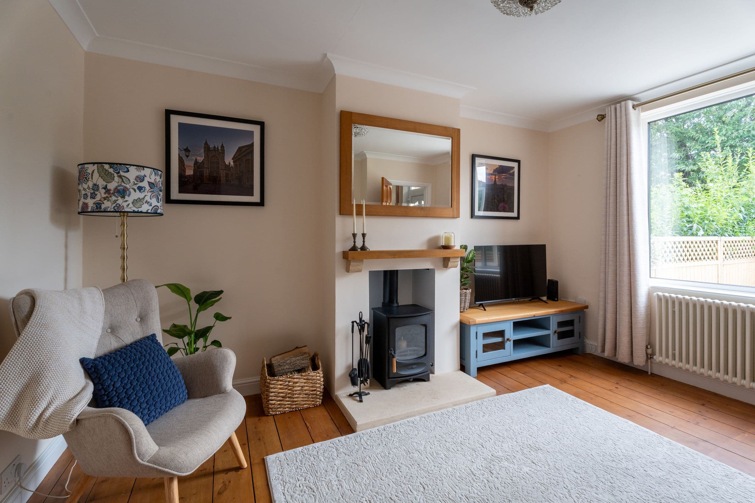 The armchair in the corner of the living room, with the rug and television unit.